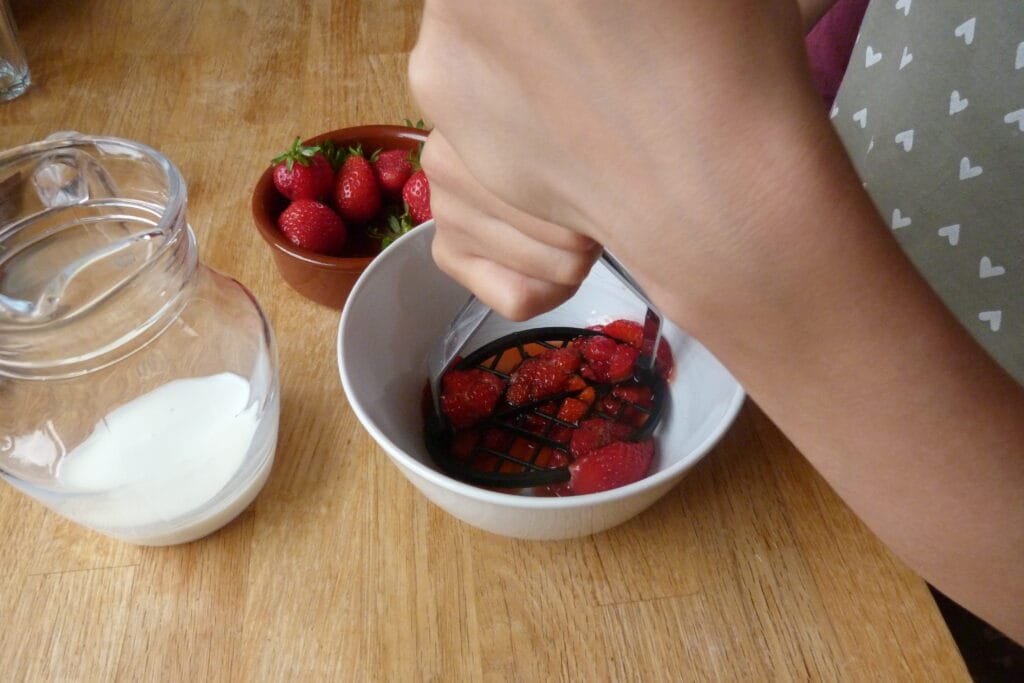 Child squashing strawberries using fine motor skills.