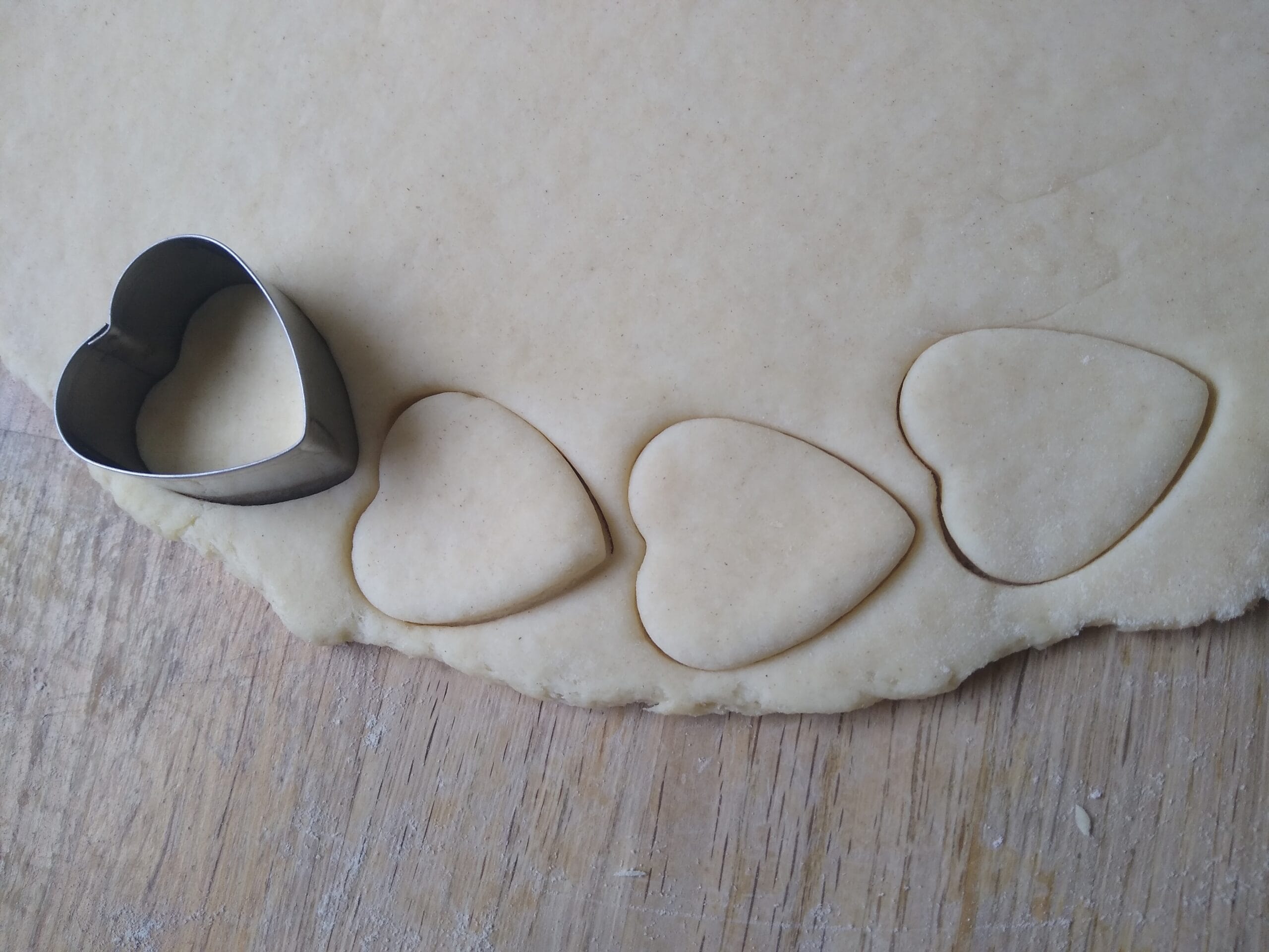 Heart-shaped cookie dough cut-outs on a wooden board