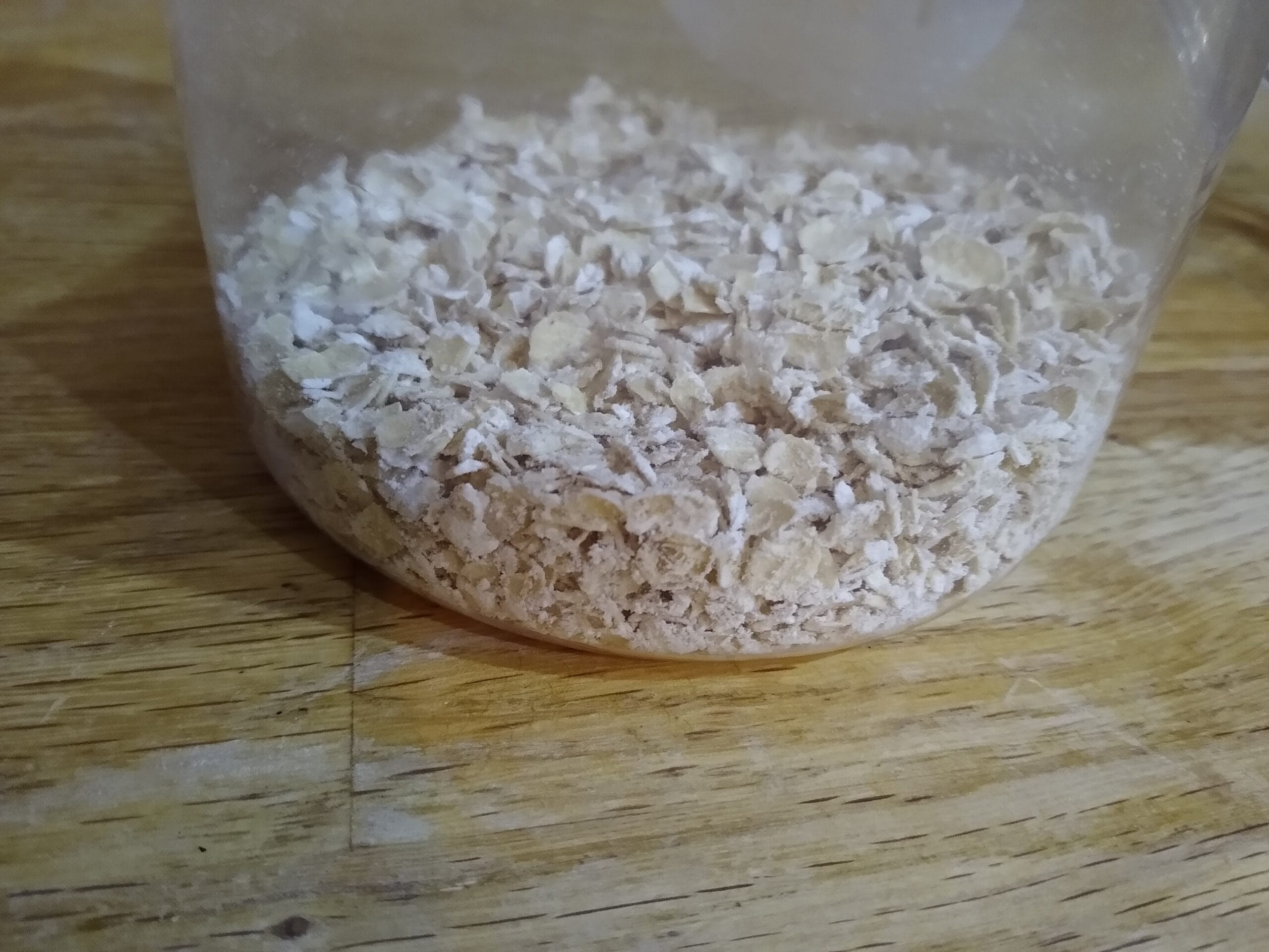 A child's hands layering oats into a glass jar for overnight oats