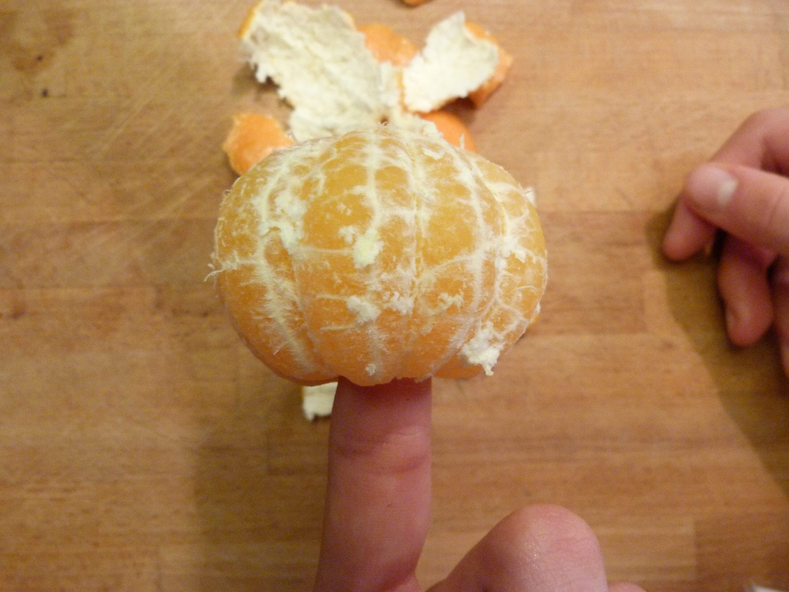 A child's hands working carefully in the kitchen — peeling an orange.  Fine motor skills in children.