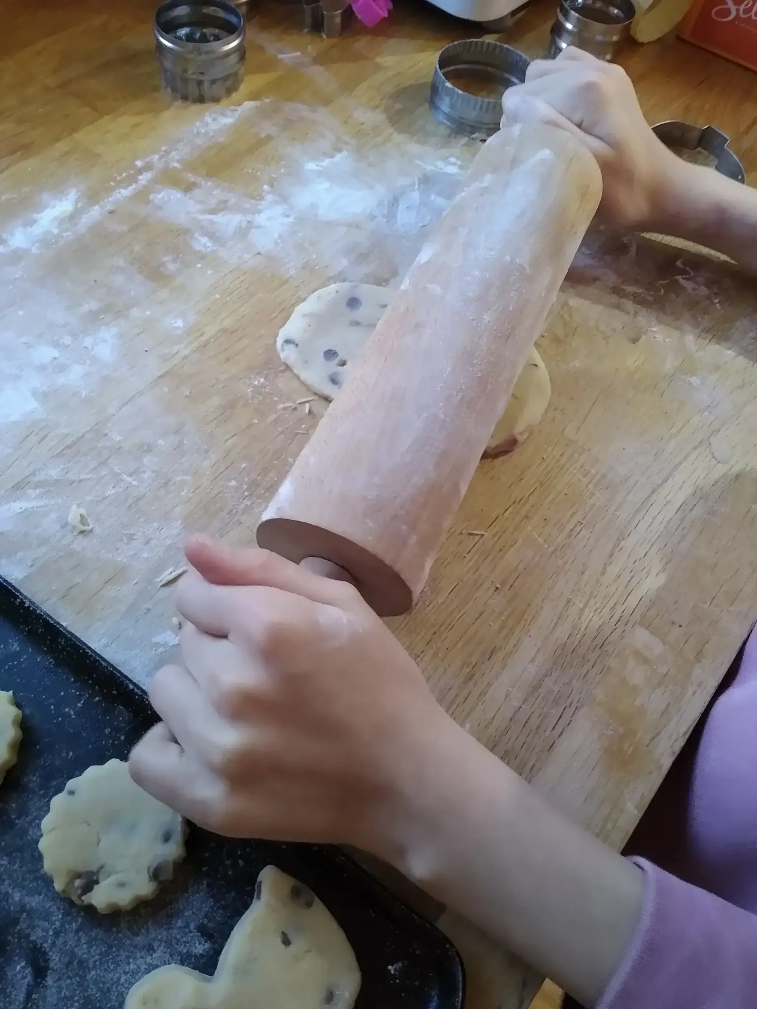 Child rolling out shortbread biscuit dough.