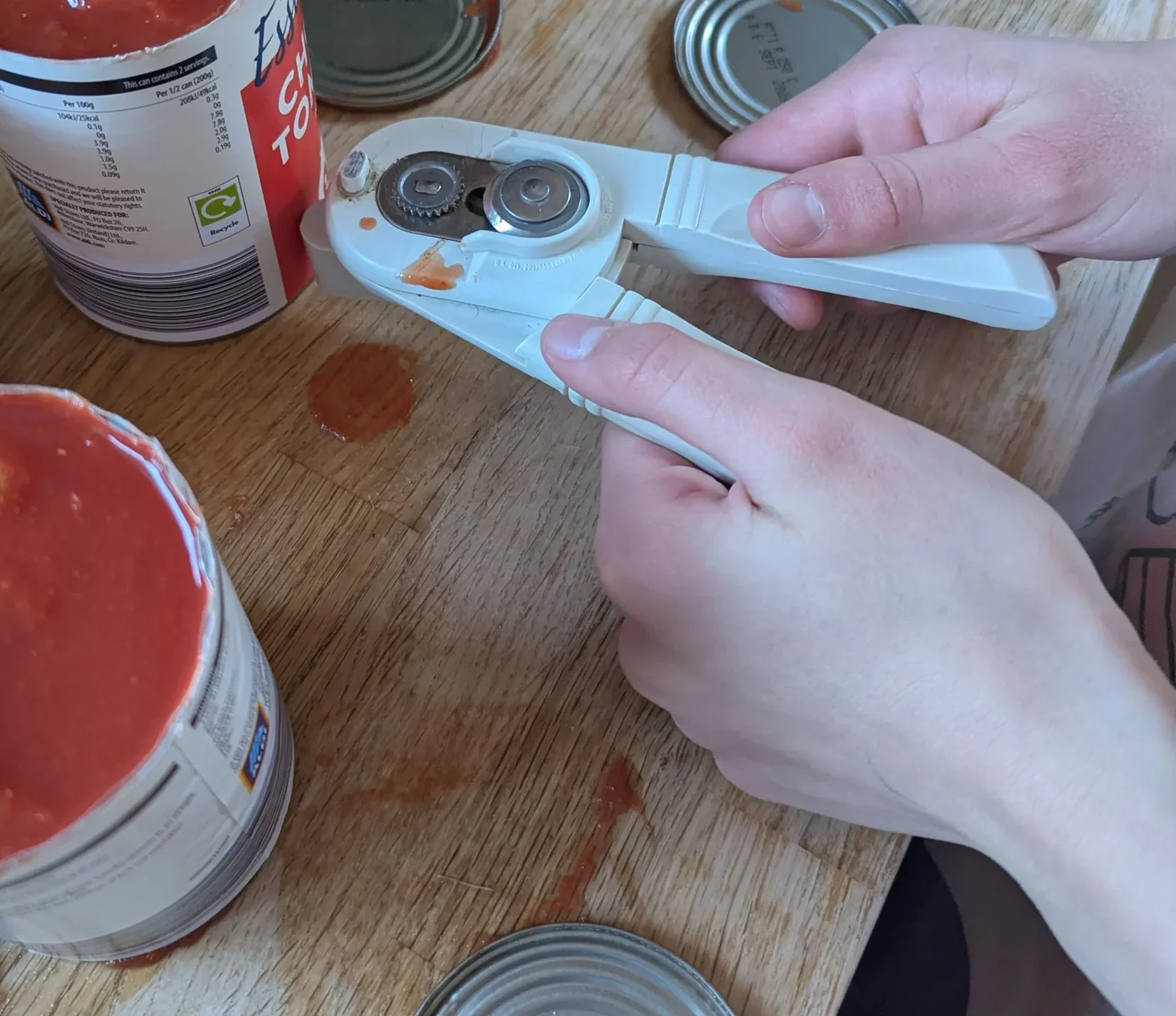 Five tins of chopped tomatoes lined up on a kitchen worktop